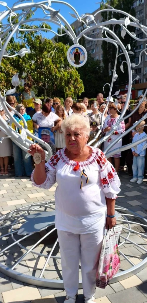 Людмила Сіроклін біля пам'ятного знаку «Символ надії», дерево символізує надію на повернення полонених та зниклих безвісти захисників. На його гілках прикріпили металеві жетони з іменами військових.