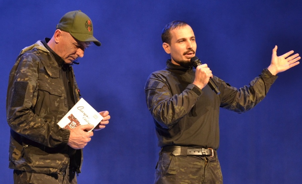 Ведучий концерту Володимир Курило з книжкою Сашка Обрія, яку було запропоновано на благодійний аукціон